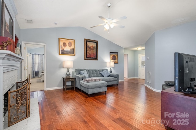 living room featuring visible vents, a fireplace, lofted ceiling, and wood-type flooring