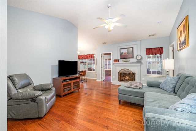 living room featuring visible vents, lofted ceiling, a fireplace, light wood-style floors, and a ceiling fan