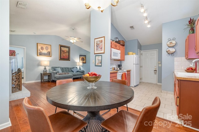 dining space with visible vents, light wood-style floors, a ceiling fan, and vaulted ceiling