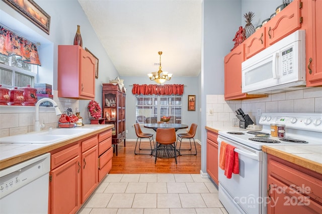 kitchen with tile counters, a chandelier, white appliances, and a sink