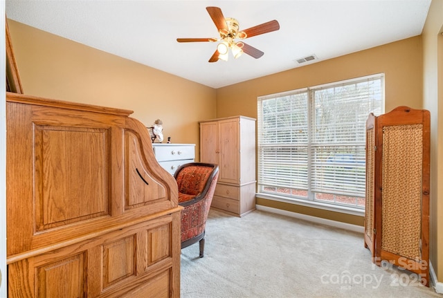 office space featuring light carpet, visible vents, a ceiling fan, and baseboards