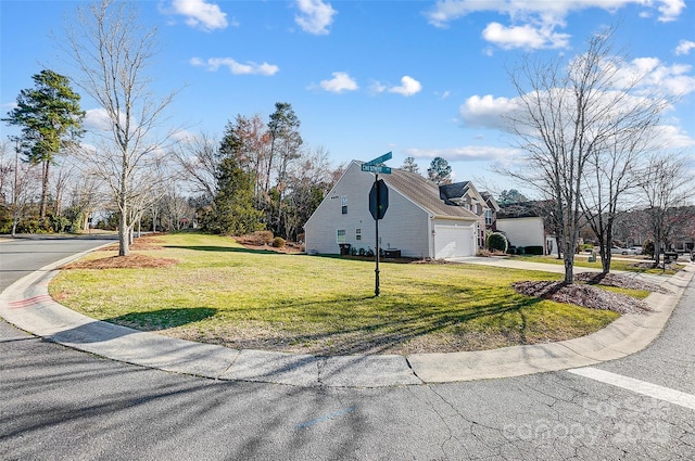 view of side of home with driveway, an attached garage, a residential view, and a yard