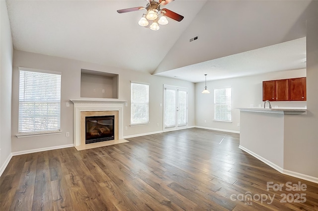 unfurnished living room with a fireplace with flush hearth, a ceiling fan, baseboards, and dark wood-style floors