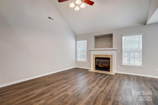 unfurnished living room featuring dark wood-style floors, a wealth of natural light, a fireplace with flush hearth, and visible vents