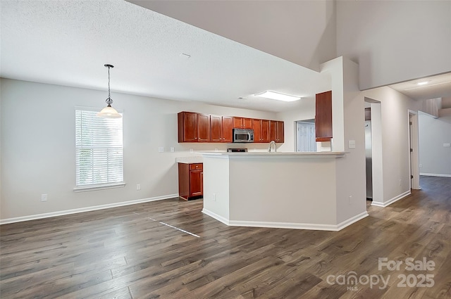 kitchen featuring dark wood-style floors, decorative light fixtures, light countertops, stainless steel microwave, and baseboards