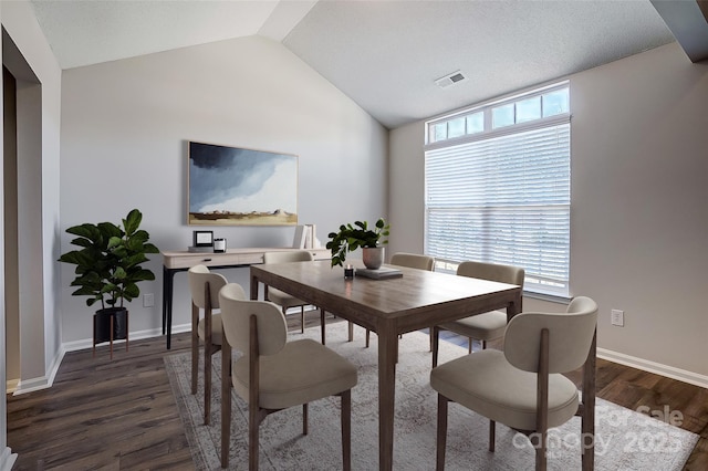 dining room with dark wood finished floors, visible vents, vaulted ceiling, and baseboards