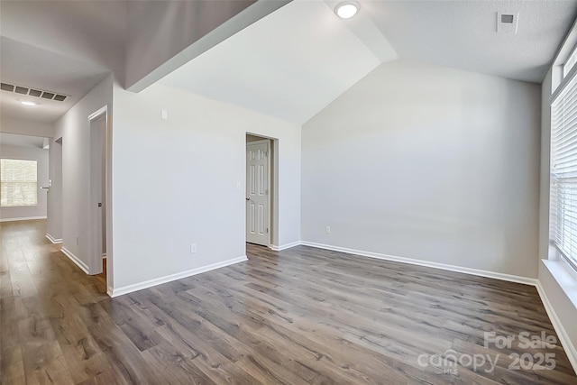 unfurnished room featuring visible vents, vaulted ceiling, baseboards, and wood finished floors