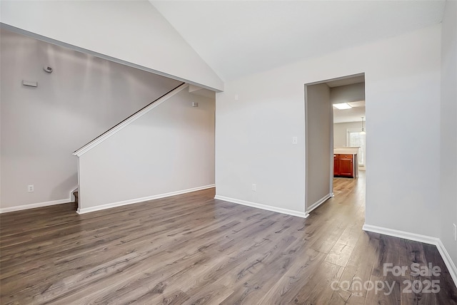 unfurnished room with lofted ceiling, baseboards, and wood finished floors