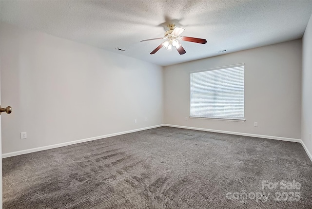 empty room with ceiling fan, a textured ceiling, dark carpet, and baseboards