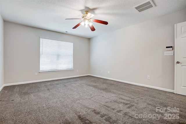 empty room featuring dark colored carpet, visible vents, a textured ceiling, and baseboards