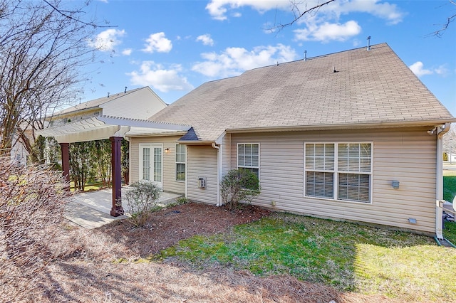 rear view of property with a shingled roof, a lawn, a patio, french doors, and a pergola