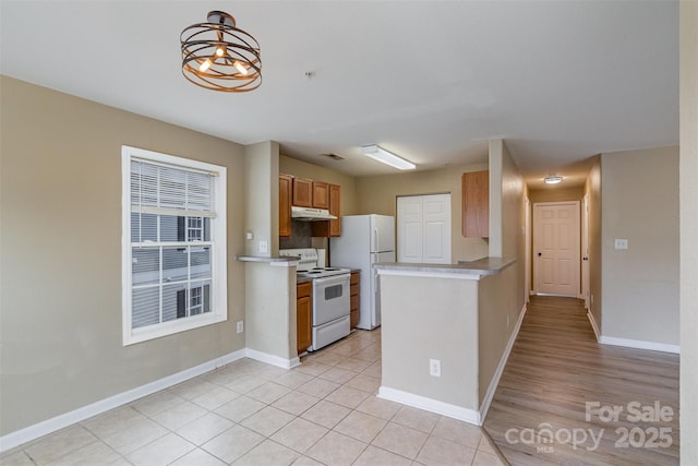 kitchen with white appliances, a notable chandelier, light tile patterned flooring, decorative light fixtures, and kitchen peninsula