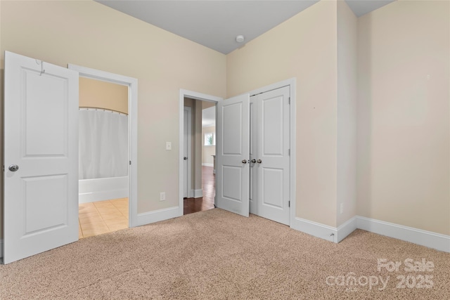 unfurnished bedroom featuring ensuite bathroom, light carpet, and a closet