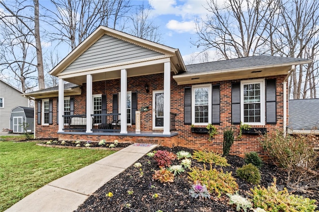 view of front of property featuring a front yard, covered porch, and a shed