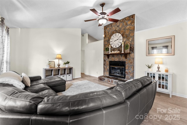 living room with a fireplace, lofted ceiling, ceiling fan, light hardwood / wood-style floors, and a textured ceiling