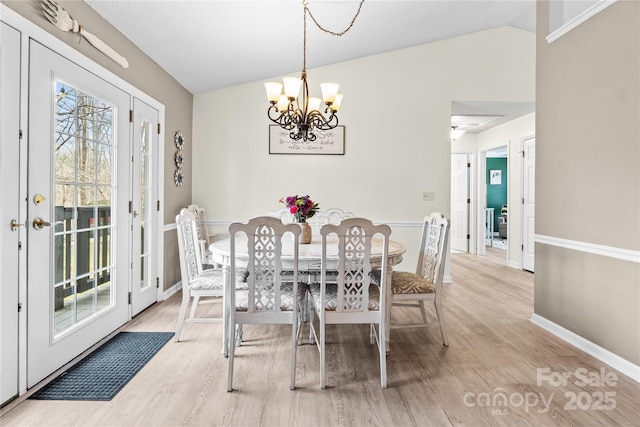 dining space with vaulted ceiling, a chandelier, and light hardwood / wood-style floors