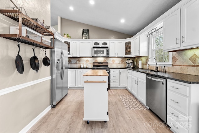 kitchen with lofted ceiling, sink, light wood-type flooring, appliances with stainless steel finishes, and white cabinets