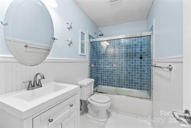 full bathroom with toilet, vanity, bath / shower combo with glass door, and a textured ceiling