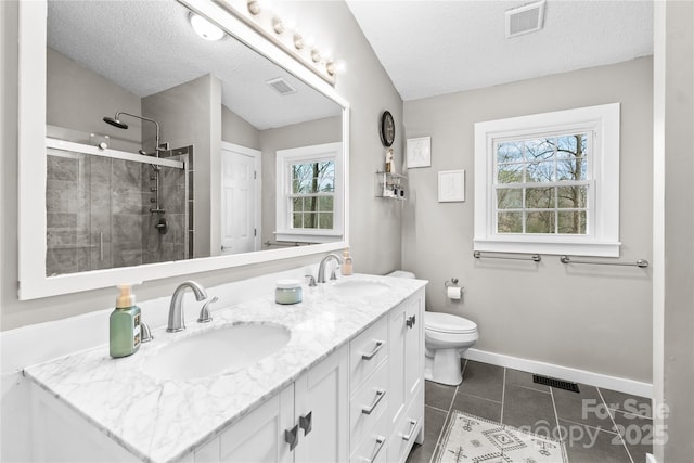 bathroom with vanity, a textured ceiling, tile patterned floors, toilet, and walk in shower