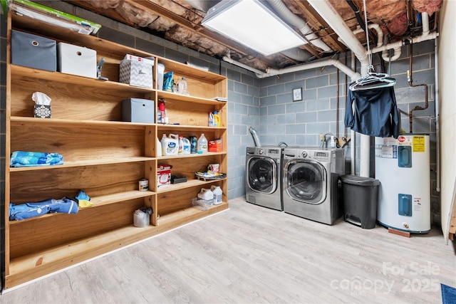 laundry area with water heater, washer and dryer, and light hardwood / wood-style floors