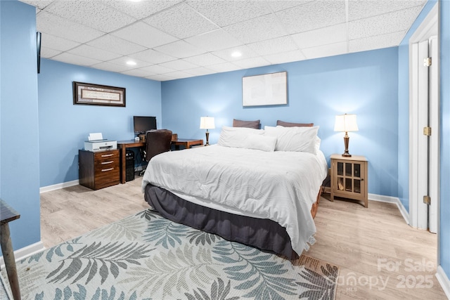 bedroom with a drop ceiling and light hardwood / wood-style flooring