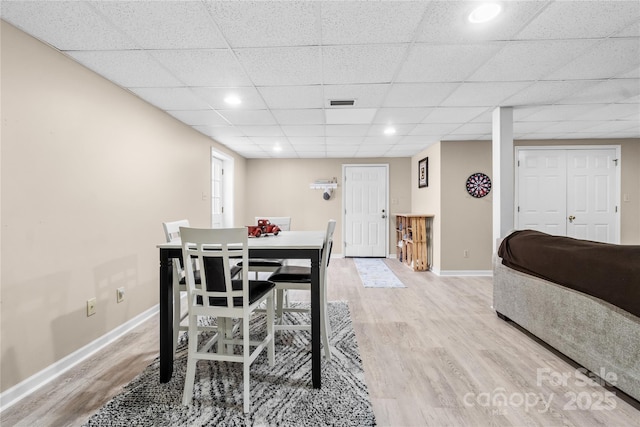 dining space with a paneled ceiling and light hardwood / wood-style floors