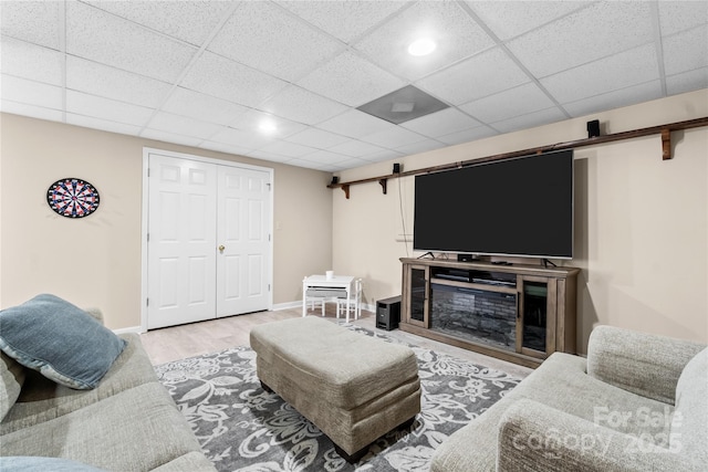 living room featuring wood-type flooring, a barn door, and a drop ceiling