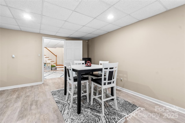 dining space with a drop ceiling and light wood-type flooring