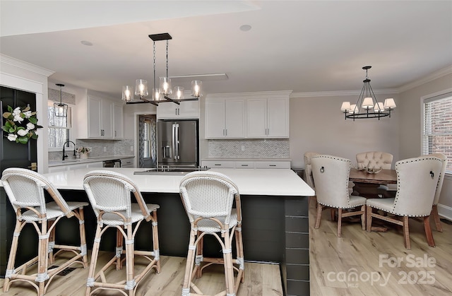 kitchen featuring white cabinetry, stainless steel refrigerator with ice dispenser, hanging light fixtures, and a center island