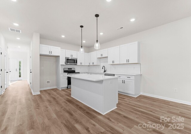 2825 New Pineola Rd Unit 7A, Charlotte, NC 28208 - kitchen with light wood finished floors, a sink, stainless steel appliances, white cabinets, and tasteful backsplash