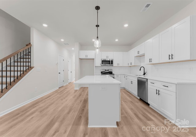 2825 New Pineola Rd Unit 7A, Charlotte, NC 28208 - kitchen with light wood finished floors, visible vents, a sink, white cabinetry, and appliances with stainless steel finishes