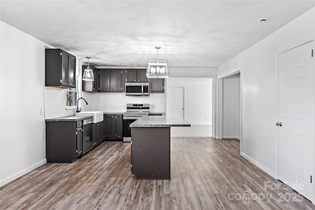 kitchen featuring hanging light fixtures, sink, stainless steel appliances, and a center island
