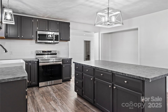 kitchen featuring dark wood-type flooring, sink, a center island, hanging light fixtures, and appliances with stainless steel finishes