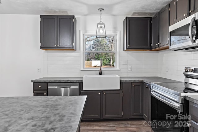 kitchen with dark wood-type flooring, sink, hanging light fixtures, stainless steel appliances, and decorative backsplash