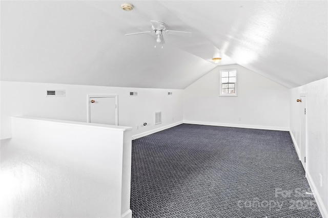 additional living space featuring ceiling fan, vaulted ceiling, and dark colored carpet