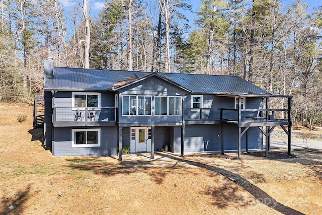 chalet / cabin featuring a deck, a chimney, a front lawn, and metal roof