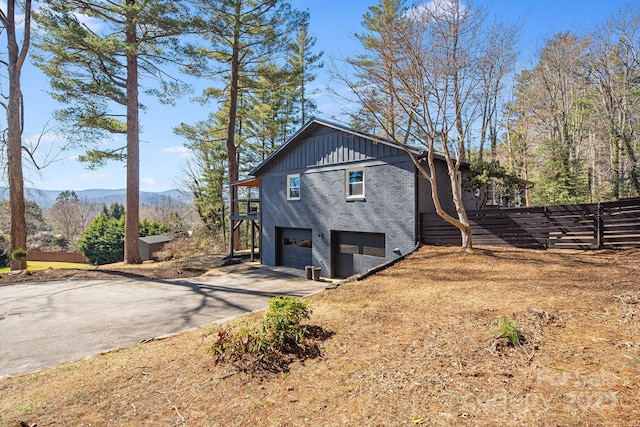 view of side of home with a mountain view, a garage, brick siding, driveway, and board and batten siding