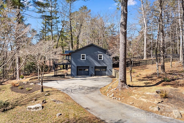 chalet / cabin featuring driveway, an attached garage, and fence