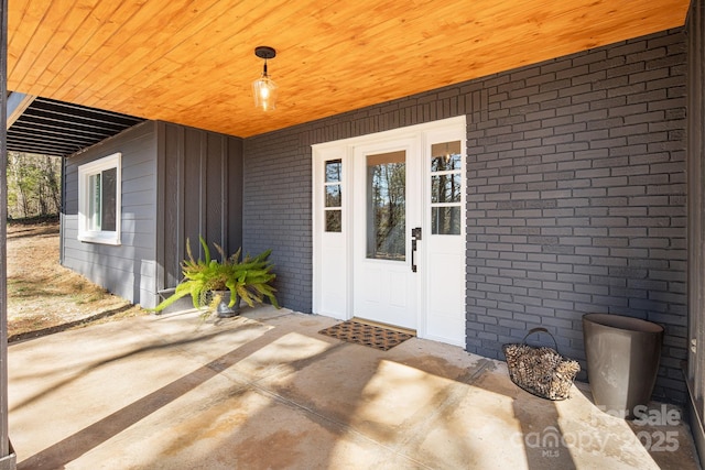 entrance to property featuring a patio and brick siding