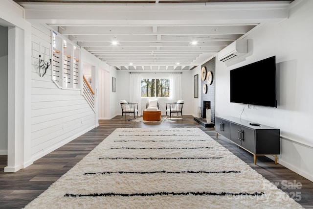 living room featuring a fireplace, stairway, a wall mounted AC, dark wood-type flooring, and baseboards