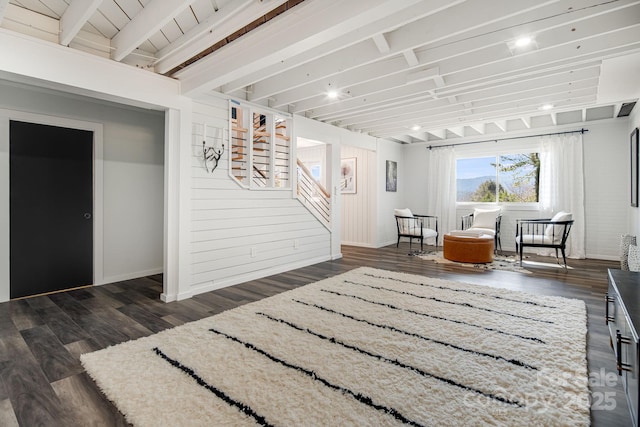 living area featuring dark wood-type flooring, stairway, and beam ceiling