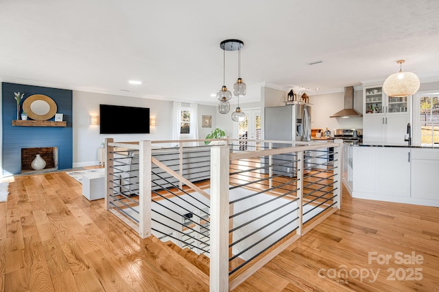 interior space with light wood finished floors, crown molding, and an upstairs landing