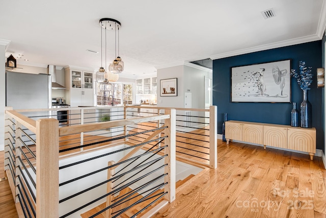 interior space with visible vents, crown molding, and an upstairs landing