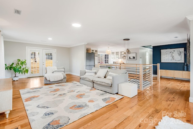 living room with a wealth of natural light, visible vents, and crown molding