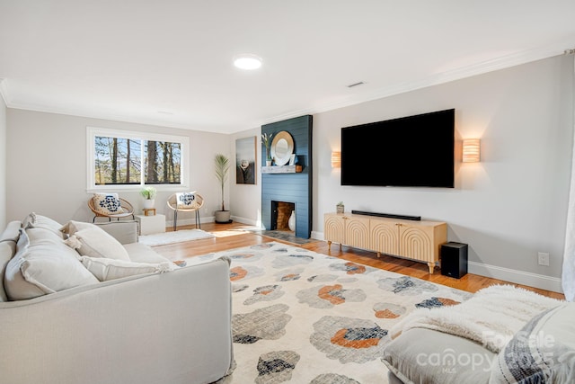 living room with a fireplace, ornamental molding, and wood finished floors