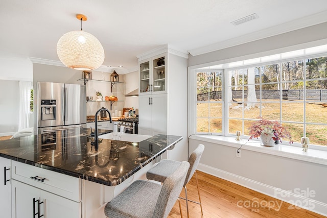 kitchen with decorative light fixtures, stainless steel appliances, visible vents, white cabinetry, and glass insert cabinets