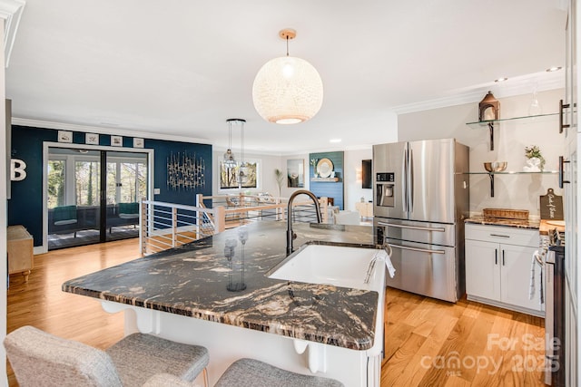 kitchen featuring a breakfast bar area, white cabinetry, appliances with stainless steel finishes, an island with sink, and pendant lighting