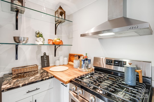 kitchen featuring dark stone counters, stainless steel gas range, extractor fan, white cabinetry, and open shelves