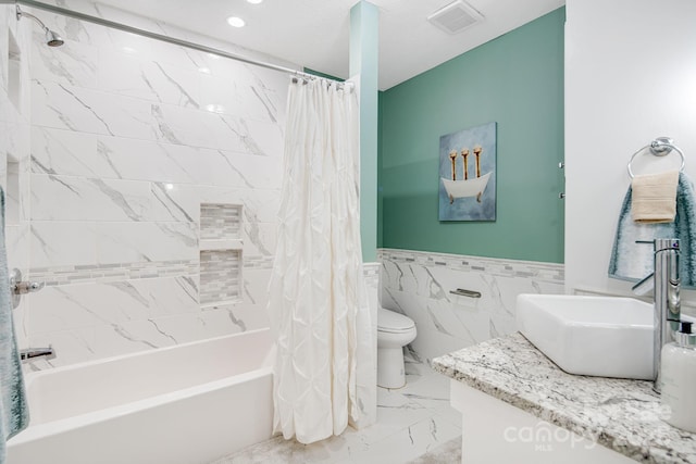 full bath featuring shower / tub combo, visible vents, toilet, a wainscoted wall, and marble finish floor