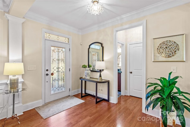 entrance foyer featuring ornate columns, baseboards, wood finished floors, and crown molding